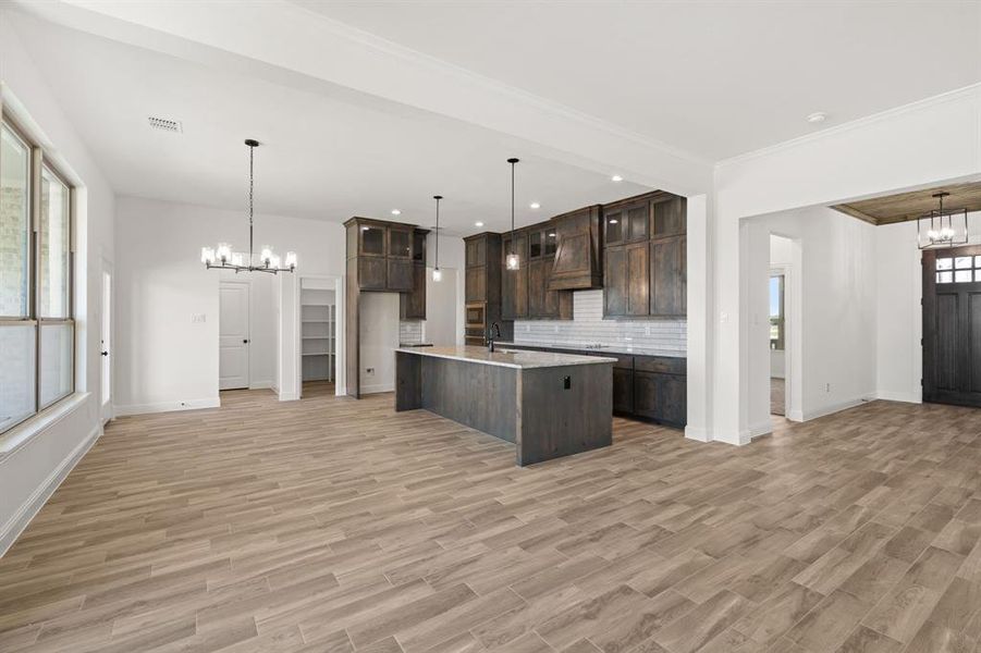 Kitchen featuring a chandelier, decorative light fixtures, glass insert cabinets, dark brown cabinets, and recessed lighting Kitchen featuring a chandelier, decorative light fixtures, glass insert cabinets, dark brown cabinets, and recessed lighting