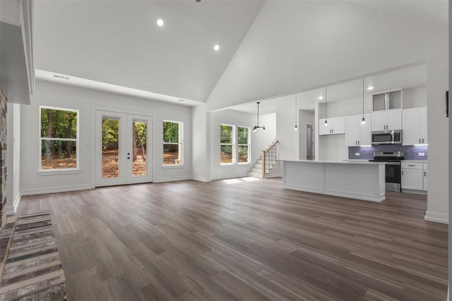 This expansive interior features vaulted ceilings, light-toned flooring, and large windows that provide views of the surrounding trees