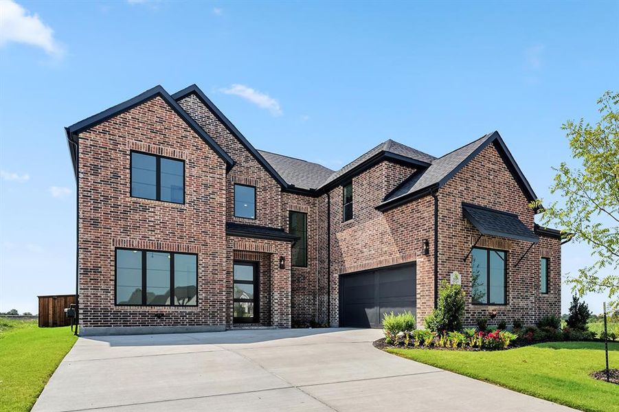 Contemporary house with concrete driveway, a front yard, and brick siding