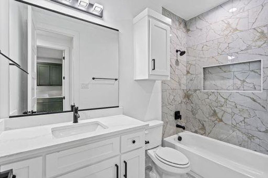 Full bathroom with vanity, tiled shower / bath combo, and toilet