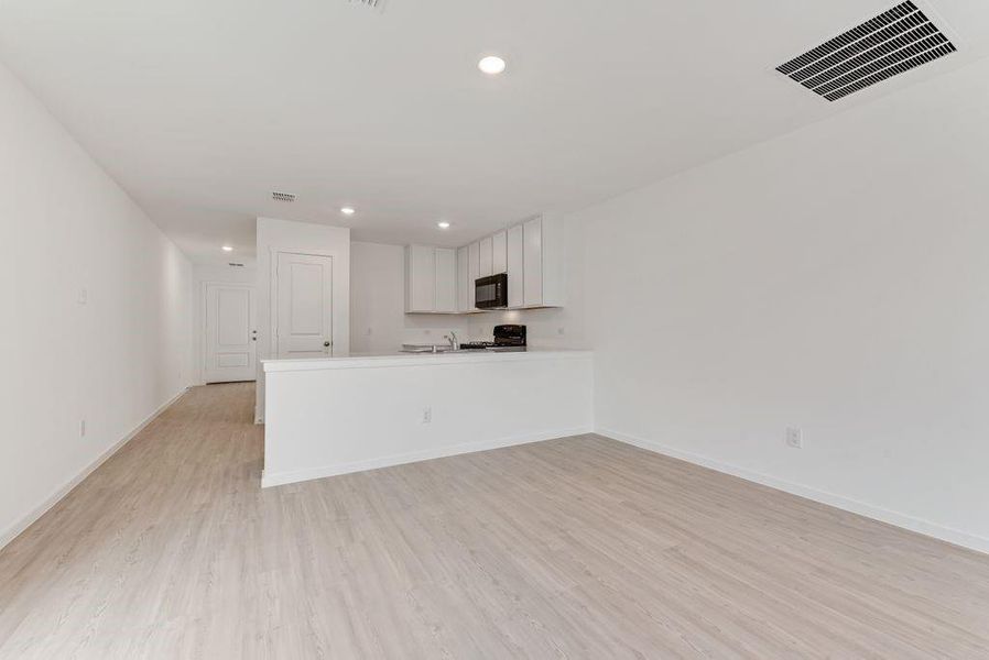 Unfurnished living room featuring light wood finished floors, baseboards, visible vents, and recessed lighting