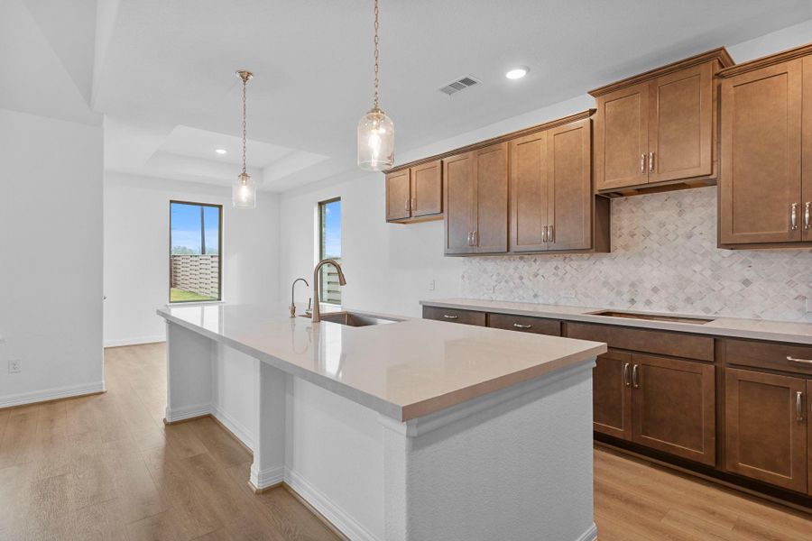 The kitchen anchors the home with deep finishes, statement textures, and an inviting layout made for gathering.