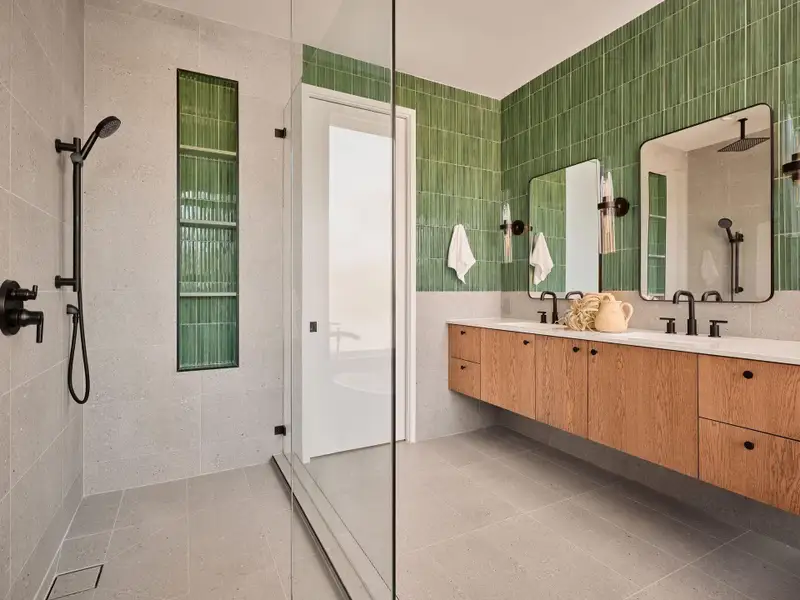 Bathroom with tiled shower, double vanity, and tile walls
