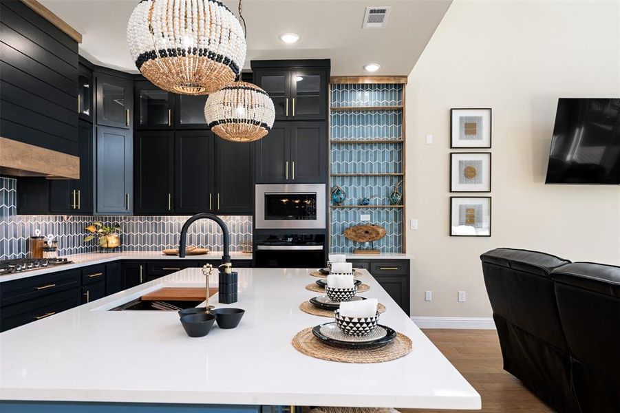 Kitchen with a center island with sink, appliances with stainless steel finishes, a notable chandelier, pendant lighting, and sink