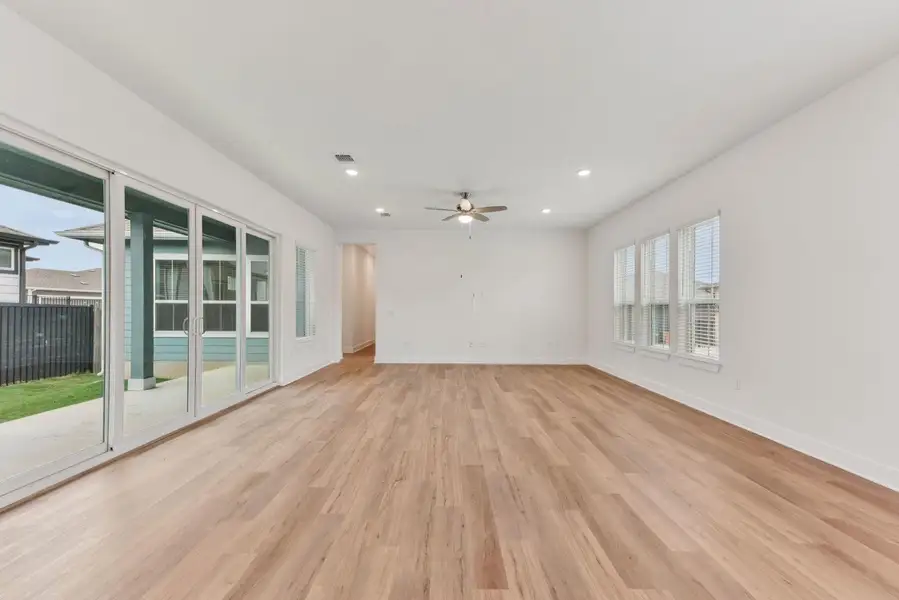 Spacious room featuring wood-finish flooring, ample natural light from multiple windows, recessed lighting, and a ceiling fan