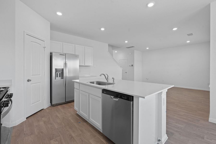 Kitchen with appliances with stainless steel finishes, white cabinetry, light wood-style floors, a kitchen island with sink, and recessed lighting Kitchen with appliances with stainless steel finishes, white cabinetry, light wood-style floors, a kitchen island with sink, and recessed lighting