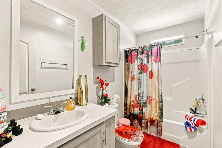 An inviting bathroom offers structured cabinetry, stone countertops, and a modern tub shower surround.