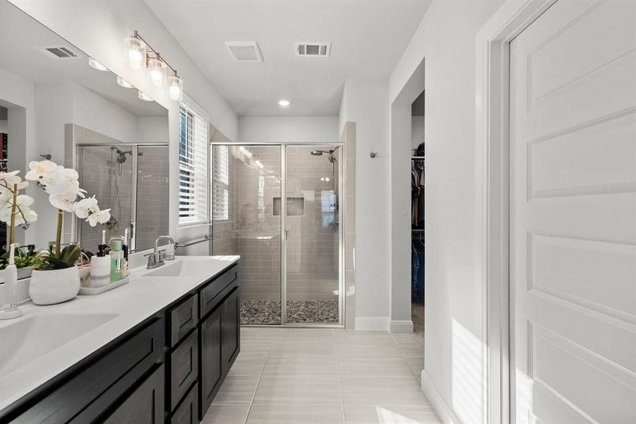 Bathroom featuring light tile patterned flooring, a stall shower, a spacious closet, and double vanity Bathroom featuring light tile patterned flooring, a stall shower, a spacious closet, and double vanity