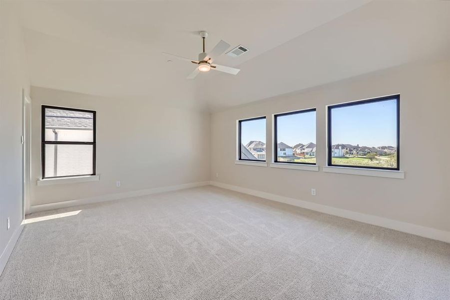 Spare room featuring light colored carpet, ceiling fan, and vaulted ceiling