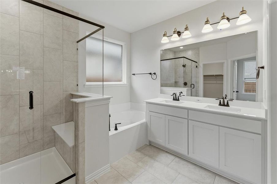 Spacious bathroom featuring a dual vanity with white cabinetry, a large frameless mirror, a separate soaking tub, and a glass-enclosed shower with a built-in bench