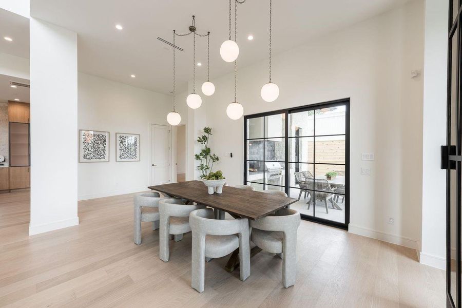 An elegant dining experience awaits beneath a sculptural chandelier that casts a warm, inviting glow over intimate gatherings and celebratory dinners alike. Framed by expansive windows and complemented by a striking glass-enclosed wine display, this space is designed for memorable evenings that linger long after dessert.