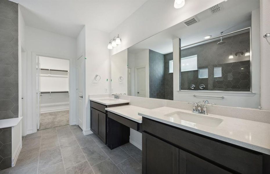 Owner's suite bathroom with dual vanity and large shower *real home pictured