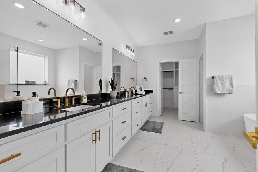 Full bathroom with a freestanding tub, a spacious closet, double vanity, light marble finish floors, and recessed lighting