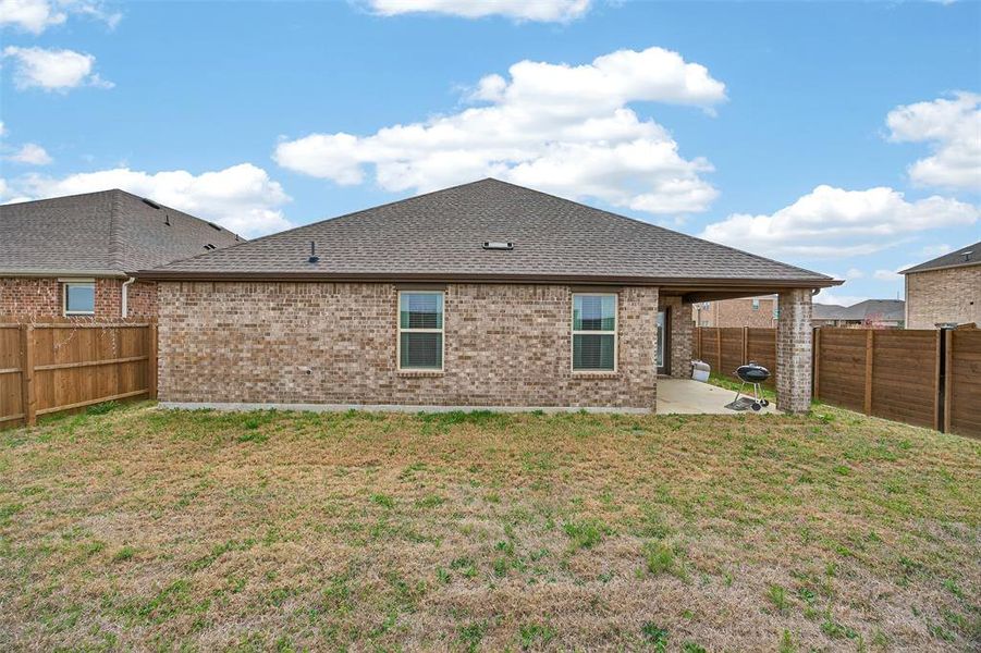 Rear view of house with a patio area, a fenced backyard, brick siding, and roof with shingles