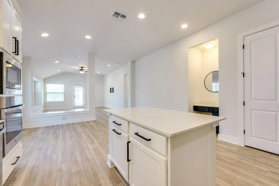 Kitchen with white cabinetry, lofted ceiling, a center island, light wood-style flooring, and recessed lighting