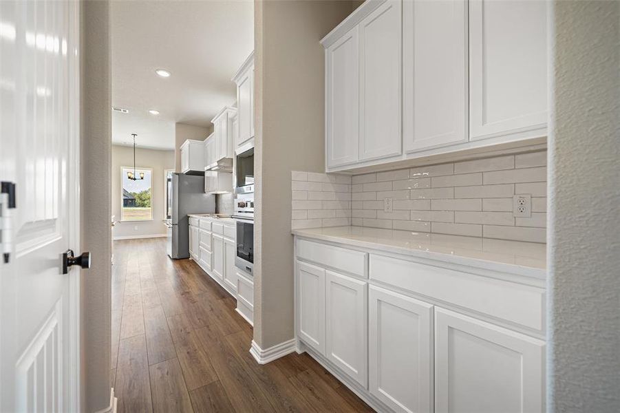 Kitchen featuring white cabinets, recessed lighting, dark wood-type flooring, backsplash, and light stone countertops