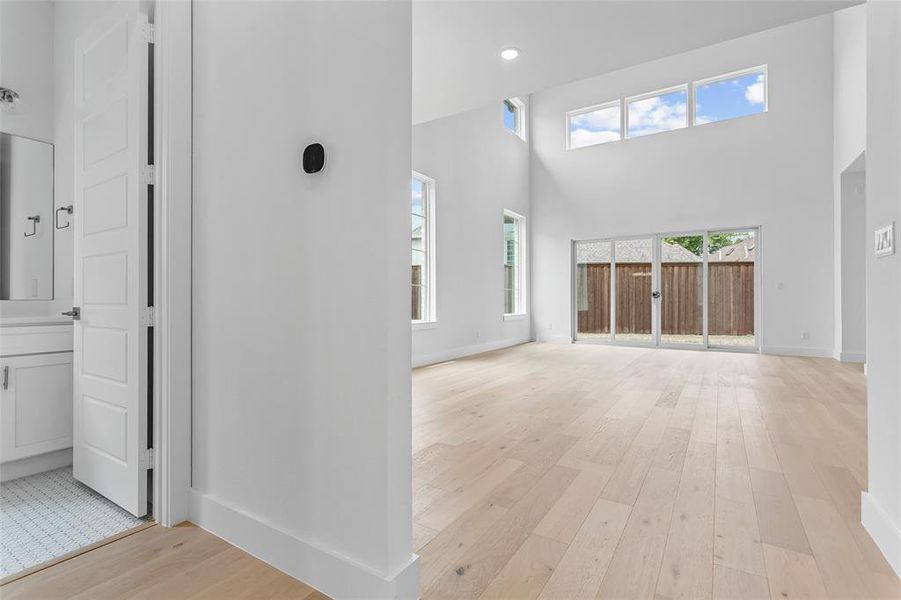 Unfurnished living room with a towering ceiling and light hardwood / wood-style floors