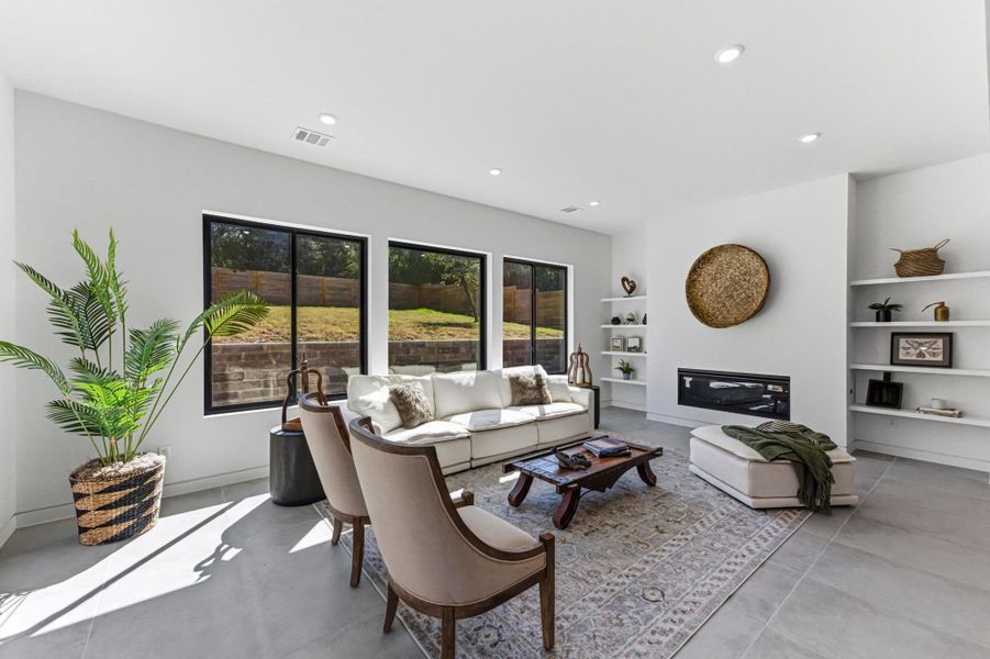 Living area featuring recessed lighting, a glass covered fireplace, and concrete floors