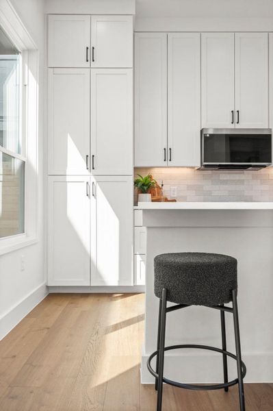 Kitchen with light wood-type flooring, white cabinetry, and light countertops