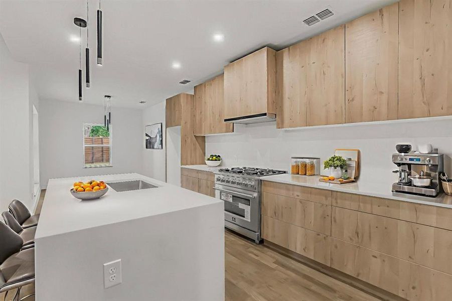 Kitchen with light brown cabinets, high end range, light wood finished floors, light countertops, and modern cabinets Kitchen with light brown cabinets, high end range, light wood finished floors, light countertops, and modern cabinets