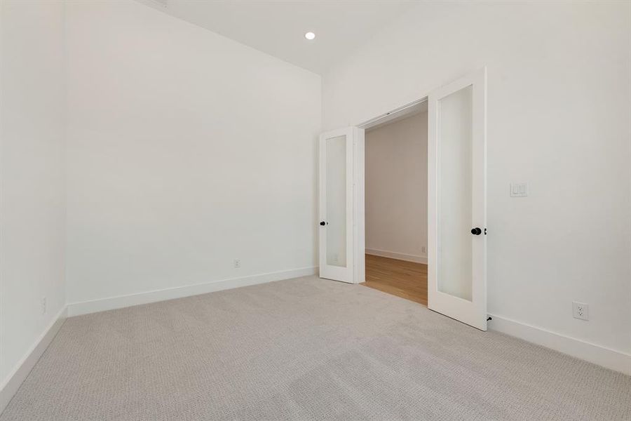 Empty room with light colored carpet, recessed lighting, and french doors Empty room with light colored carpet, recessed lighting, and french doors