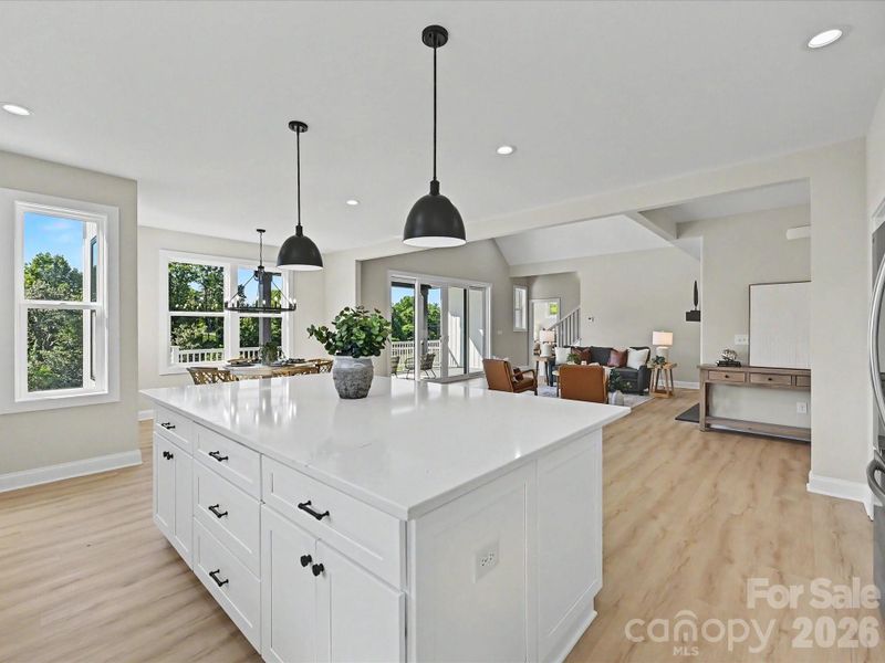 Designer kitchen and dining area showcase a massive quartz island, gas cooktop, stylish lighting, and sun-filled open layout ideal for entertaining and everyday living.