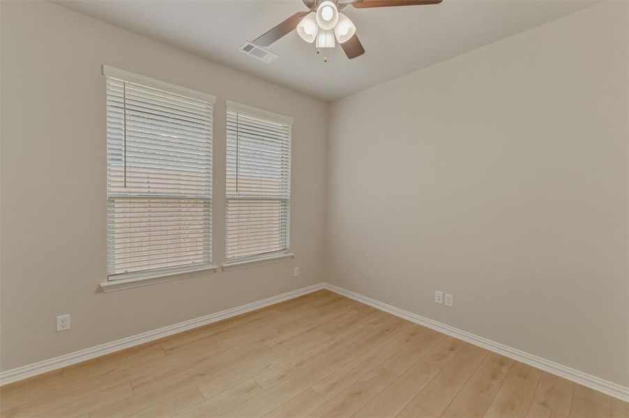 Room with wood-finish flooring, neutral wall tones, and white trim