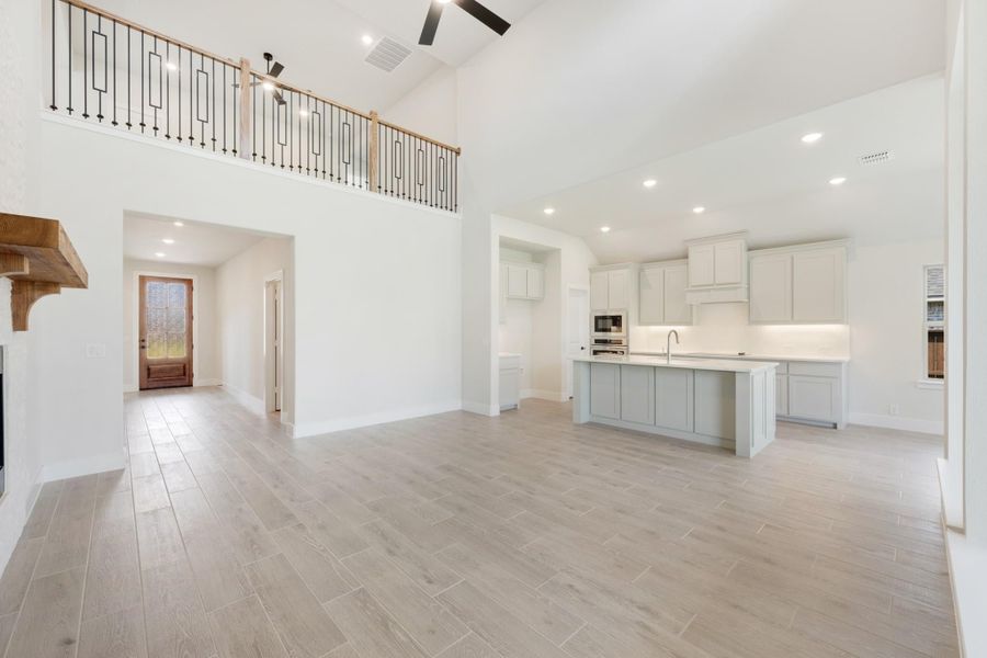 Open-concept living area with two-story ceiling, kitchen island, gray cabinets, and wood-look tile floors
