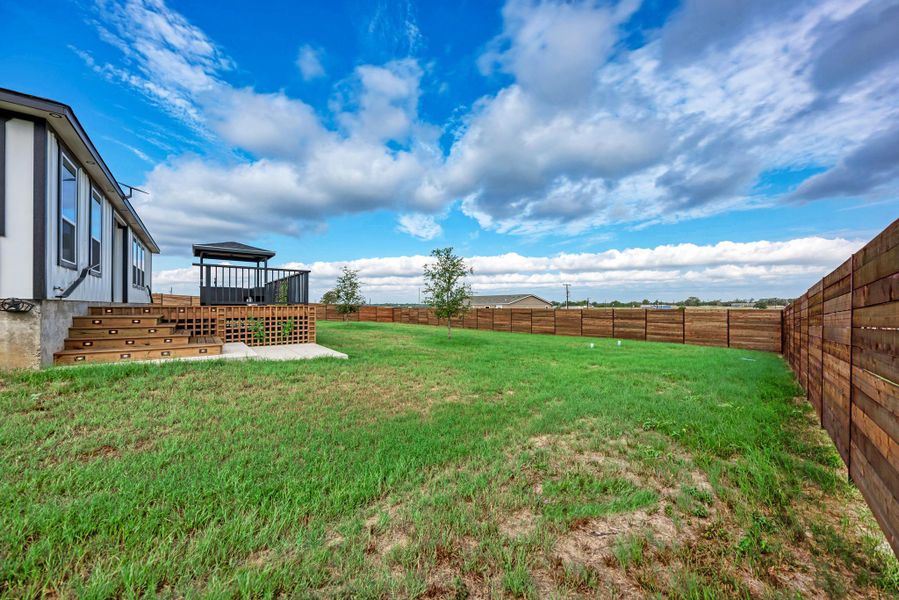 A spacious grassy yard sits enclosed by a tall wood privacy fence. A spacious grassy yard sits enclosed by a tall wood privacy fence.