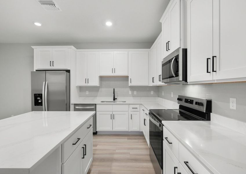 Kitchen with white cabinets, black hardware, quartz countertops and stainless steel appliances