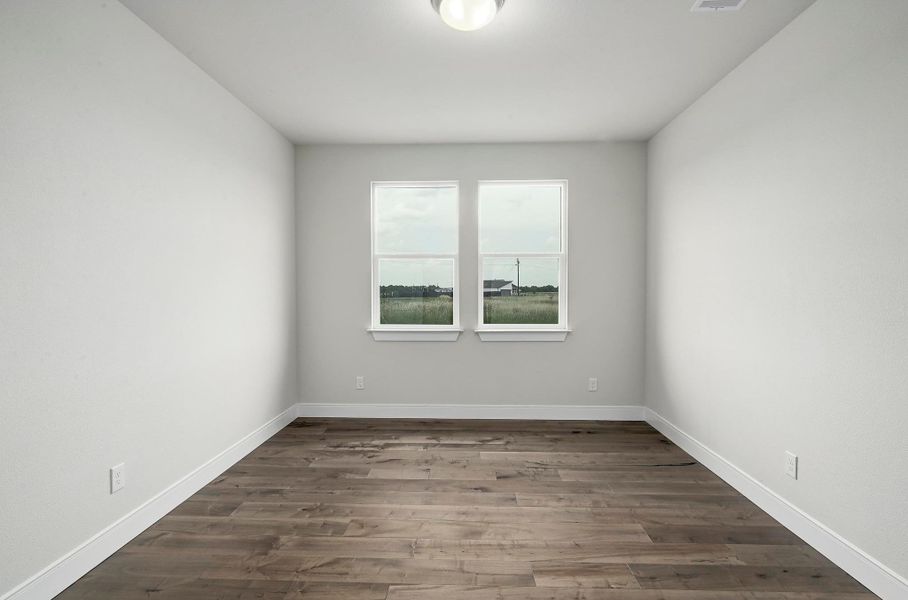 Spare room featuring dark wood-style floors and baseboards