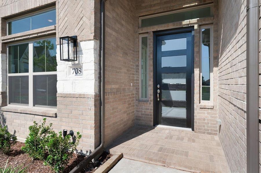 Doorway to property with bricked entry and beautiful paneled front door.
