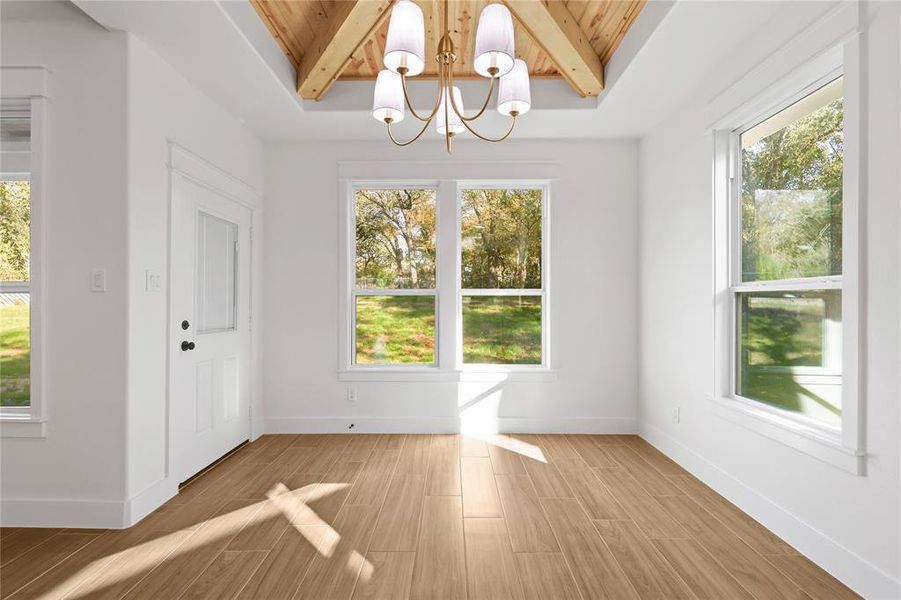 Unfurnished dining area featuring a chandelier, light wood-style floors, and a wooden ceiling with exposed beams