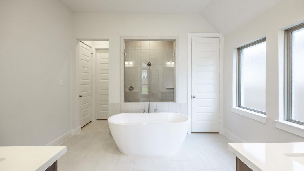 Full bath with vanity, a freestanding bath, tiled shower, and tile patterned floors Full bath with vanity, a freestanding bath, tiled shower, and tile patterned floors