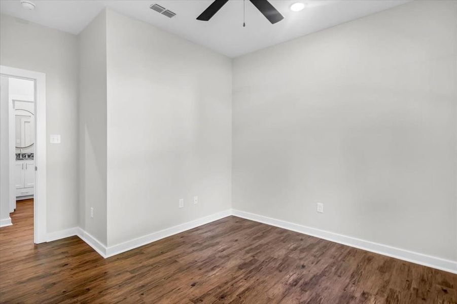 Unfurnished room with ceiling fan, baseboards, and dark wood-style floors