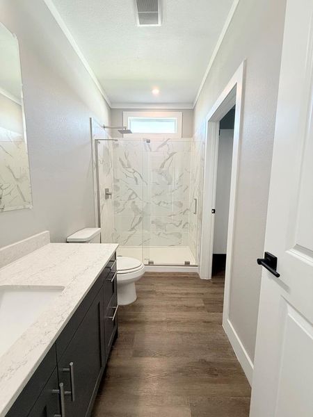 A well-appointed bathroom with a spacious vanity, walk-in shower, and natural wood-look flooring.