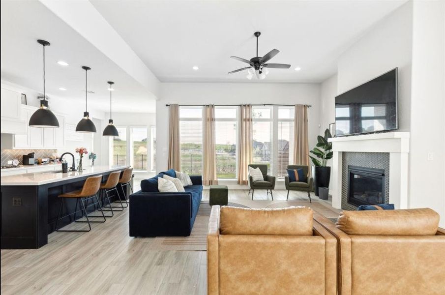 Living area featuring light wood-type flooring, recessed lighting, a tile fireplace, and a ceiling fan