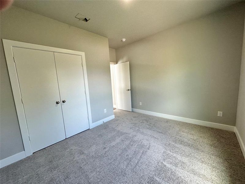 secondary upstairs bedroom featuring a closet and light colored carpet