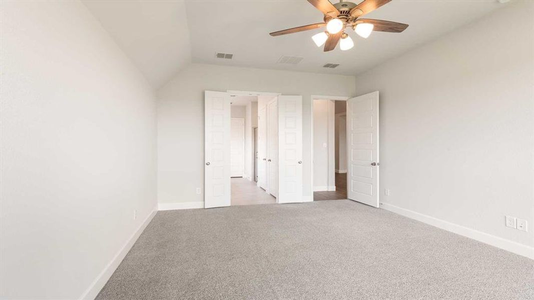 Unfurnished bedroom with lofted ceiling, ceiling fan, and light colored carpet