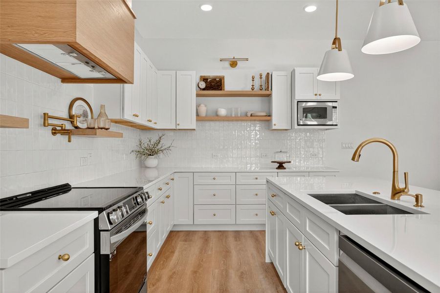 Kitchen with stainless steel appliances, open shelves, white cabinets, and recessed lighting