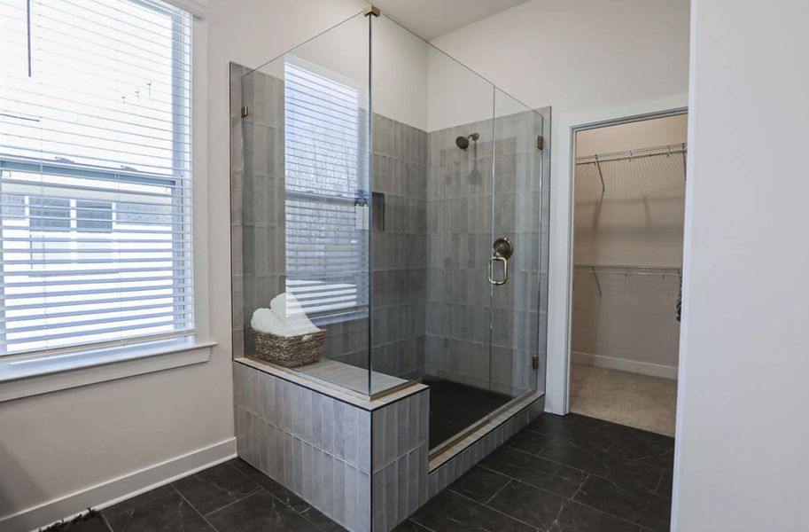 Glass-enclosed shower featuring vertical tile work, a built-in bench, and bronze fixtures