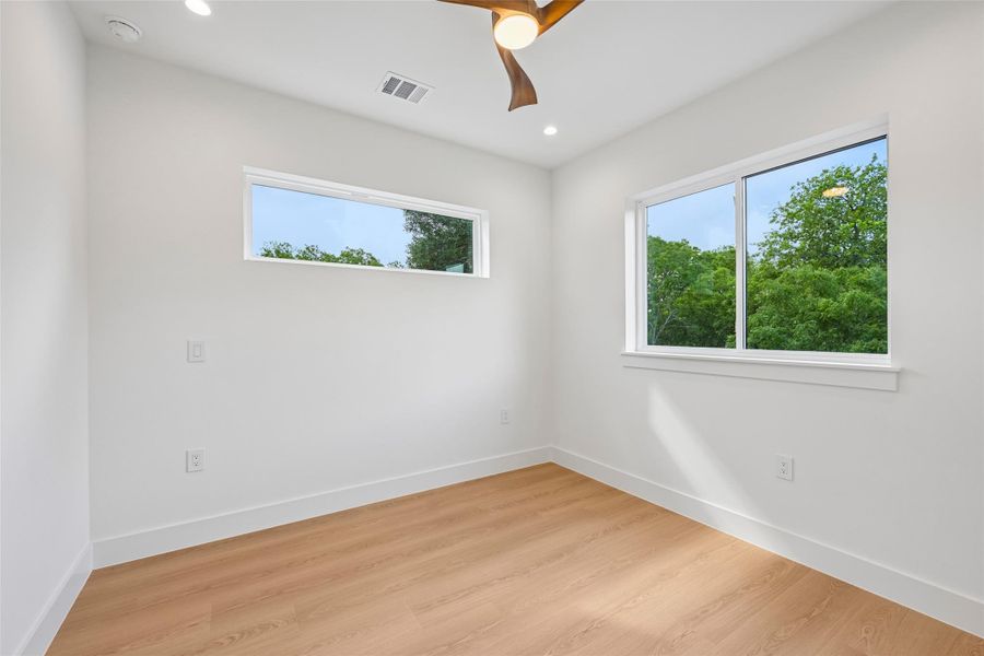 An airy bedroom with contemporary light-colored flooring and a refreshing wooden ceiling fan.