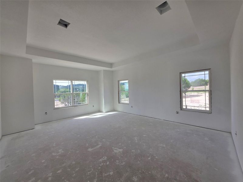 Spacious room featuring multiple windows, a tray ceiling, and recessed lighting