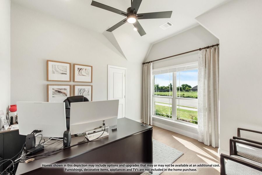 Home office with vaulted ceiling, ceiling fan, large window, and dark wood desk with dual monitors