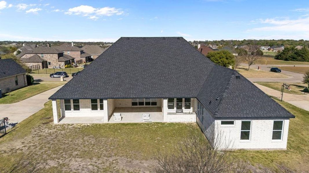 Back of house with a patio, a lawn, a residential view, and a shingled roof