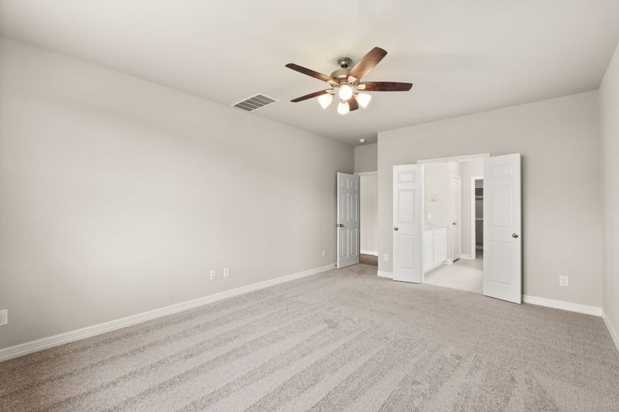 An additional view of the primary bedroom features two double doors leading to the en-suite bath and walk-in closet.