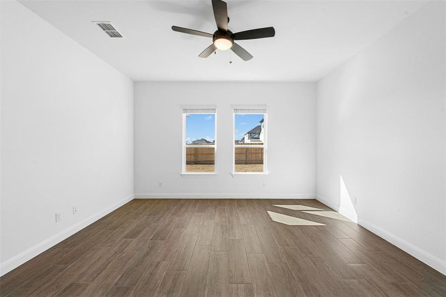 Bright interior space featuring wood-finish flooring, white baseboards, and a ceiling fan with integrated lighting