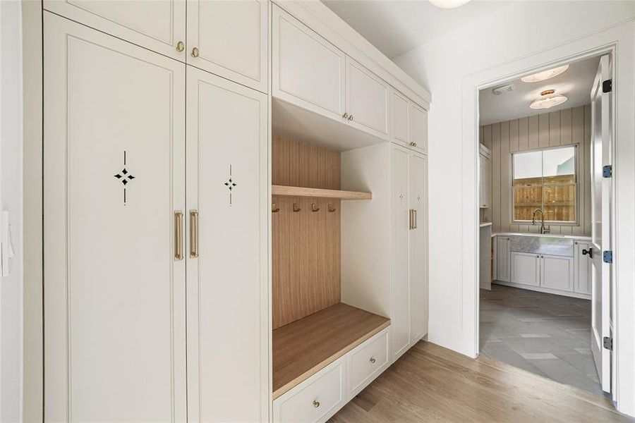 Built-in cabinetry with decorative accents, wood-finish flooring, and a dedicated mudroom bench with storage