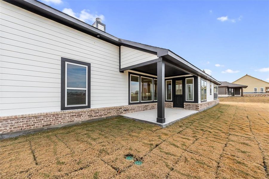 Rear view of property featuring brick siding, a patio, and a yard