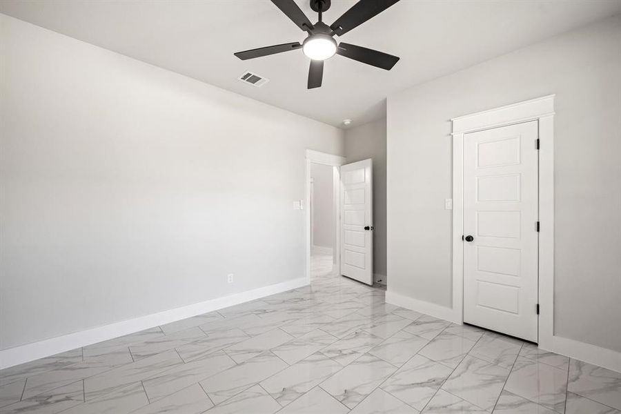 Unfurnished bedroom featuring light marble finish floors and a ceiling fan